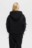 Person wearing a black hoodie with unique design elements on a plain background