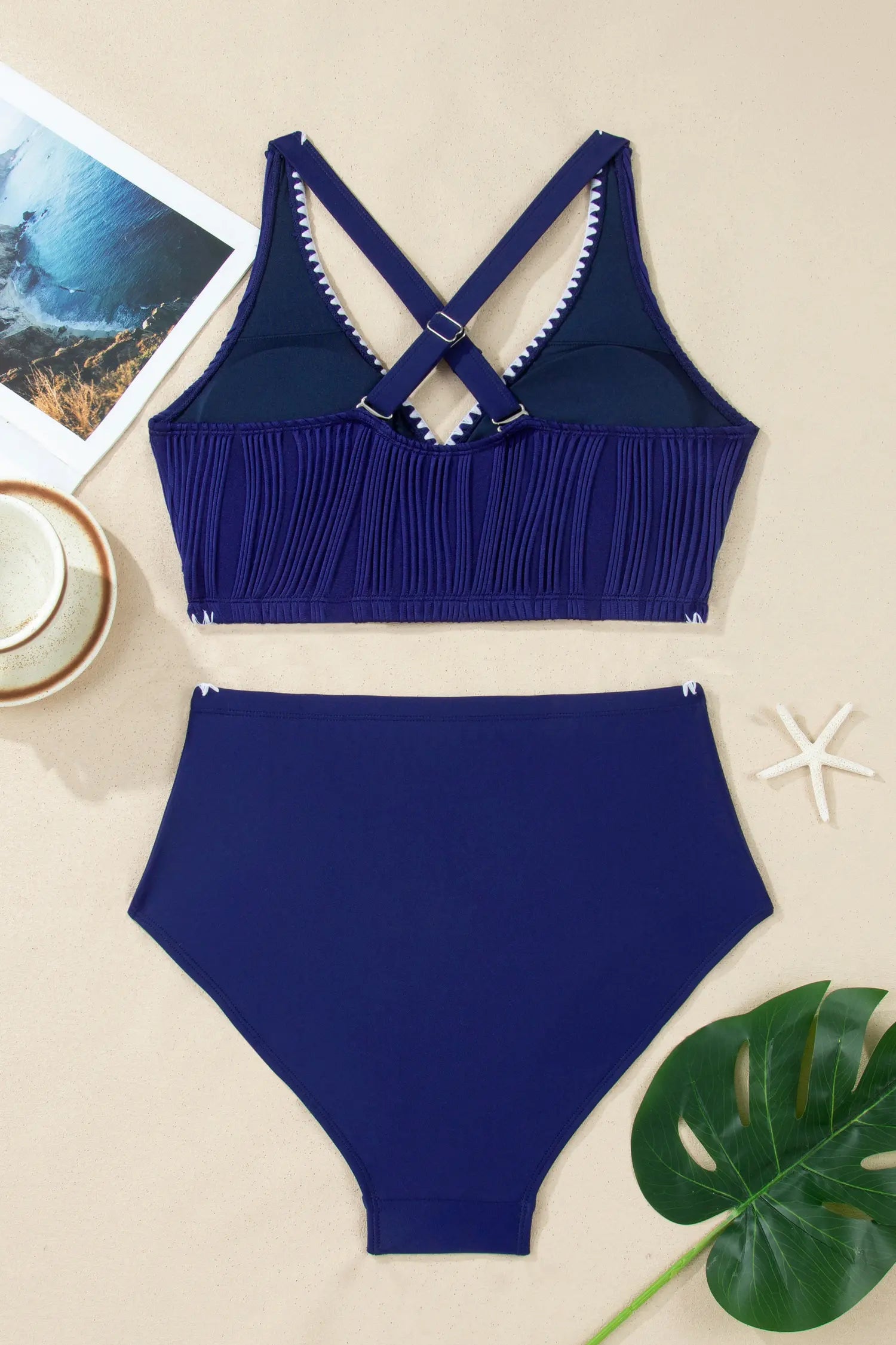 Blue bikini set on a beige surface with a starfish and leaf.