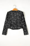 Black sequin top on a hanger against a white background