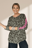 Woman wearing a leopard print sweater with pink stripes on a plain background