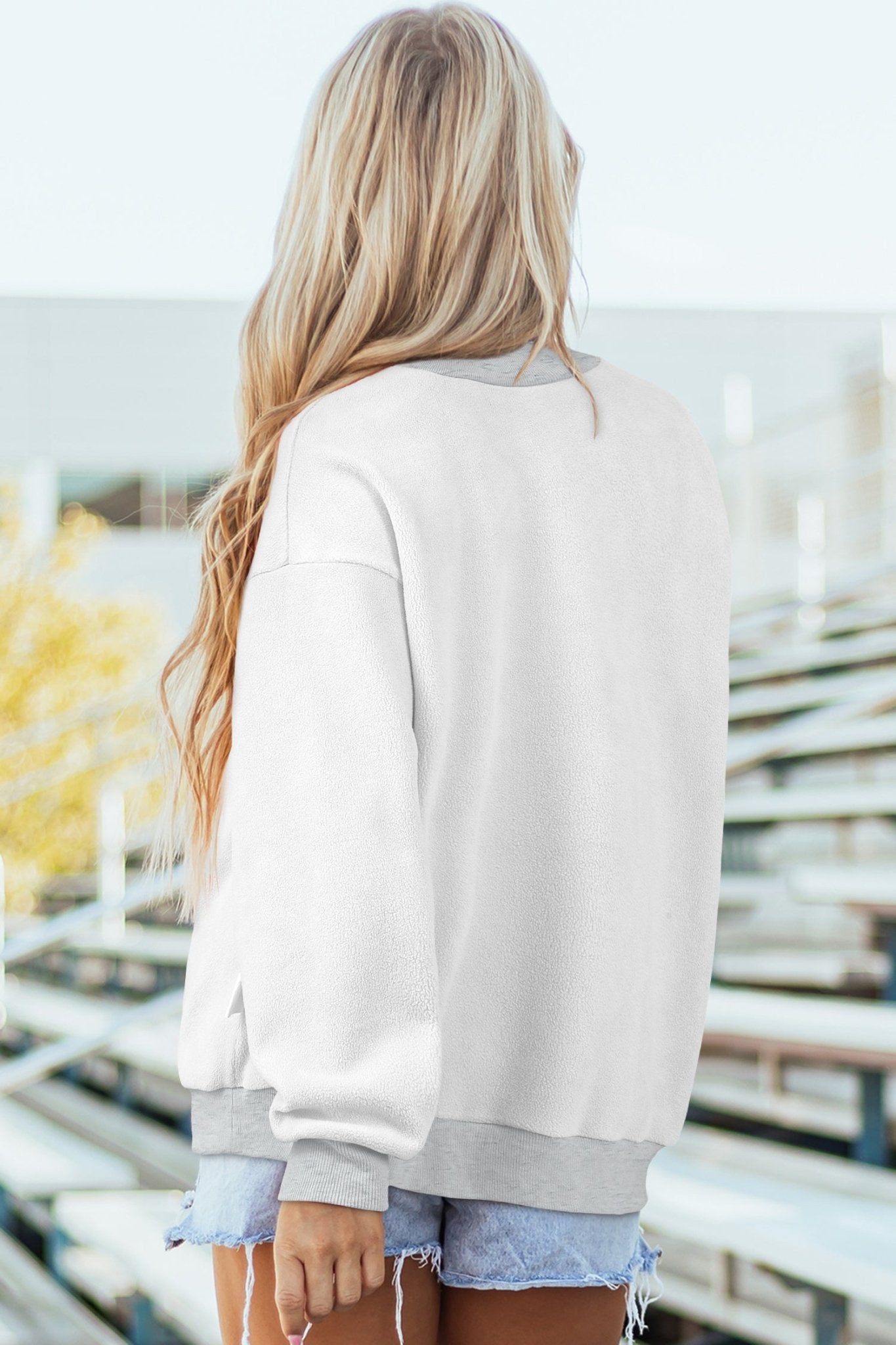 Person wearing a light gray sweatshirt with a blurred indoor background