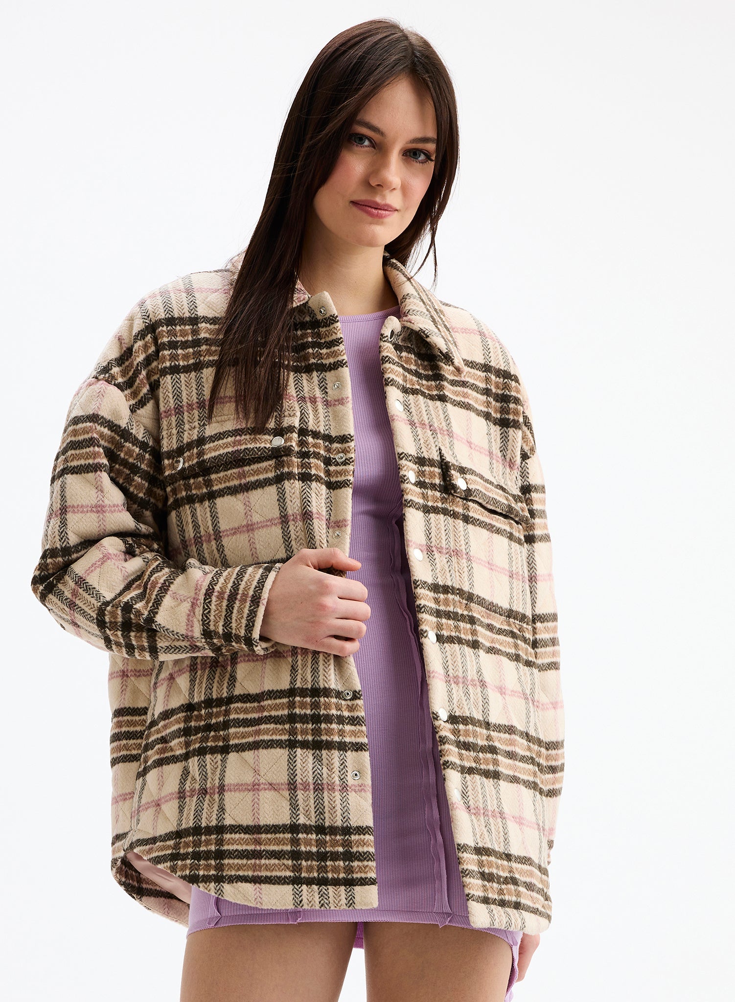 Woman wearing a plaid jacket over a purple dress on a white background