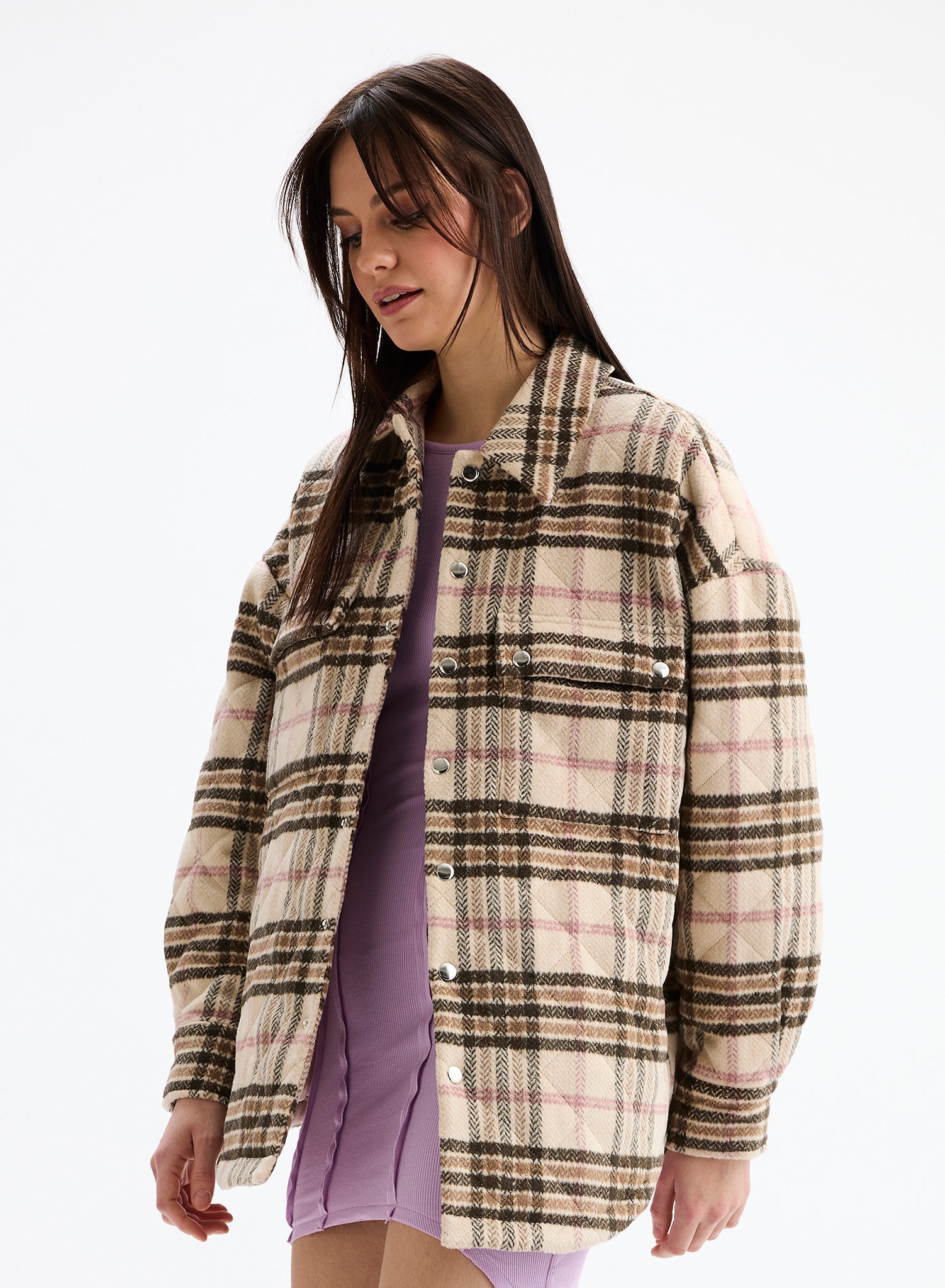 Woman wearing a plaid shirt over a purple dress on a white background