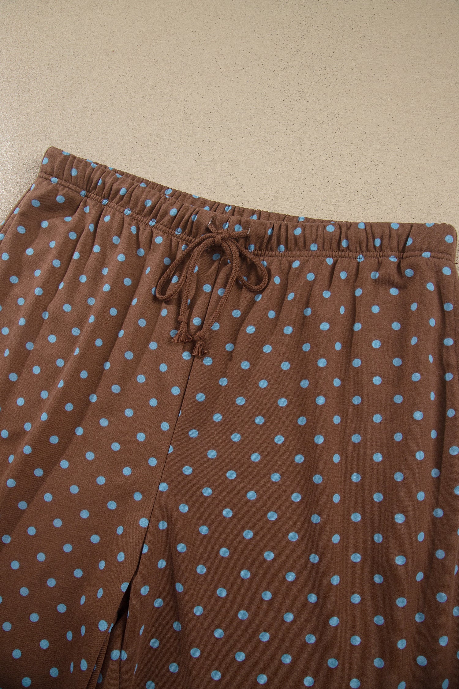 Brown lounge pants with light blue polka dots and an elastic drawstring waistband.