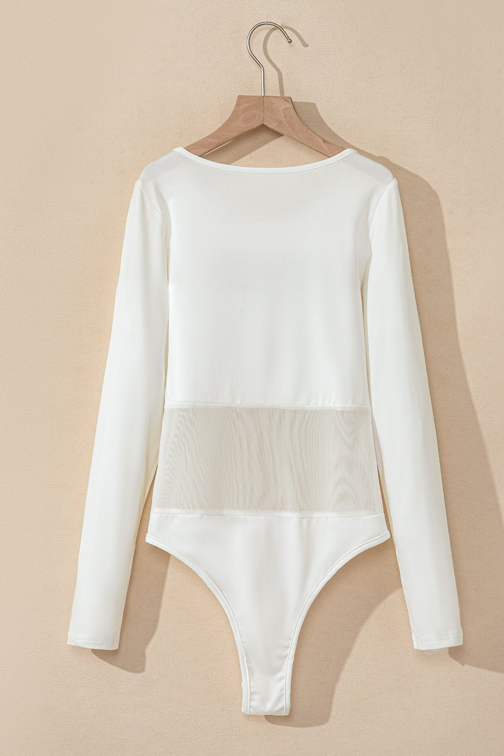 White long-sleeve bodysuit on a beige background
