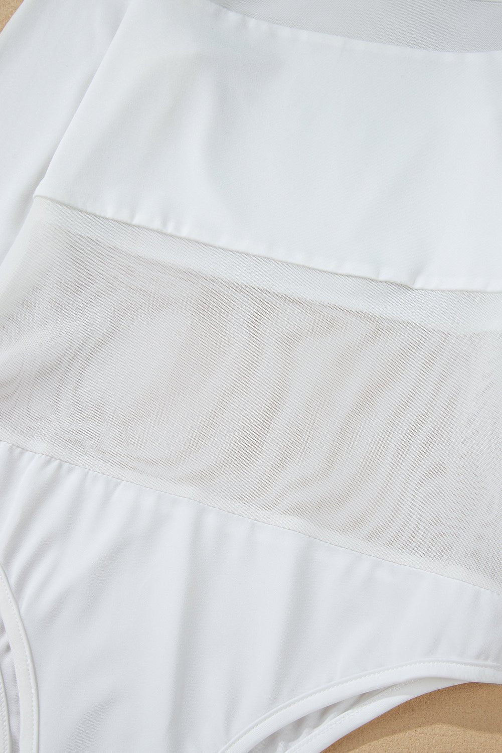 Close-up of white underwear with a beige waistband on a wooden surface.