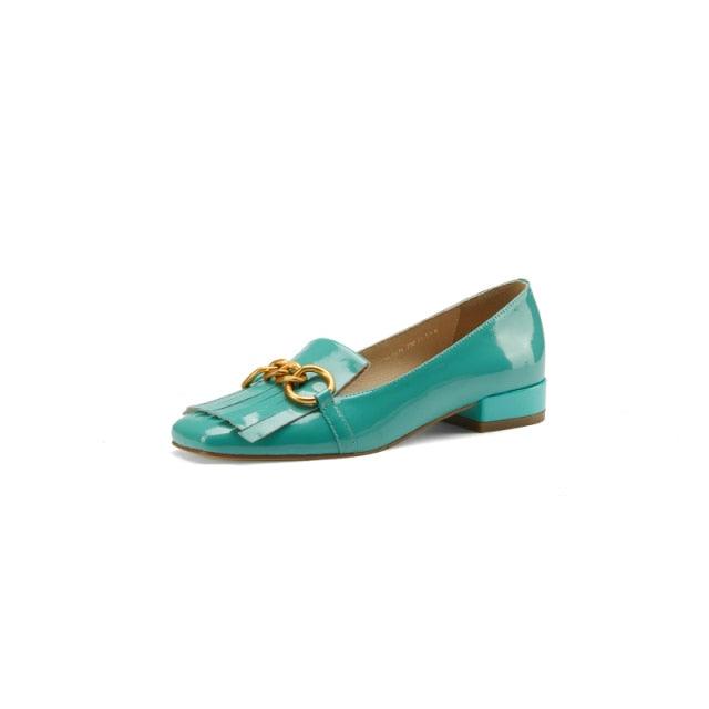 Teal shoe with gold chain detail on a white background