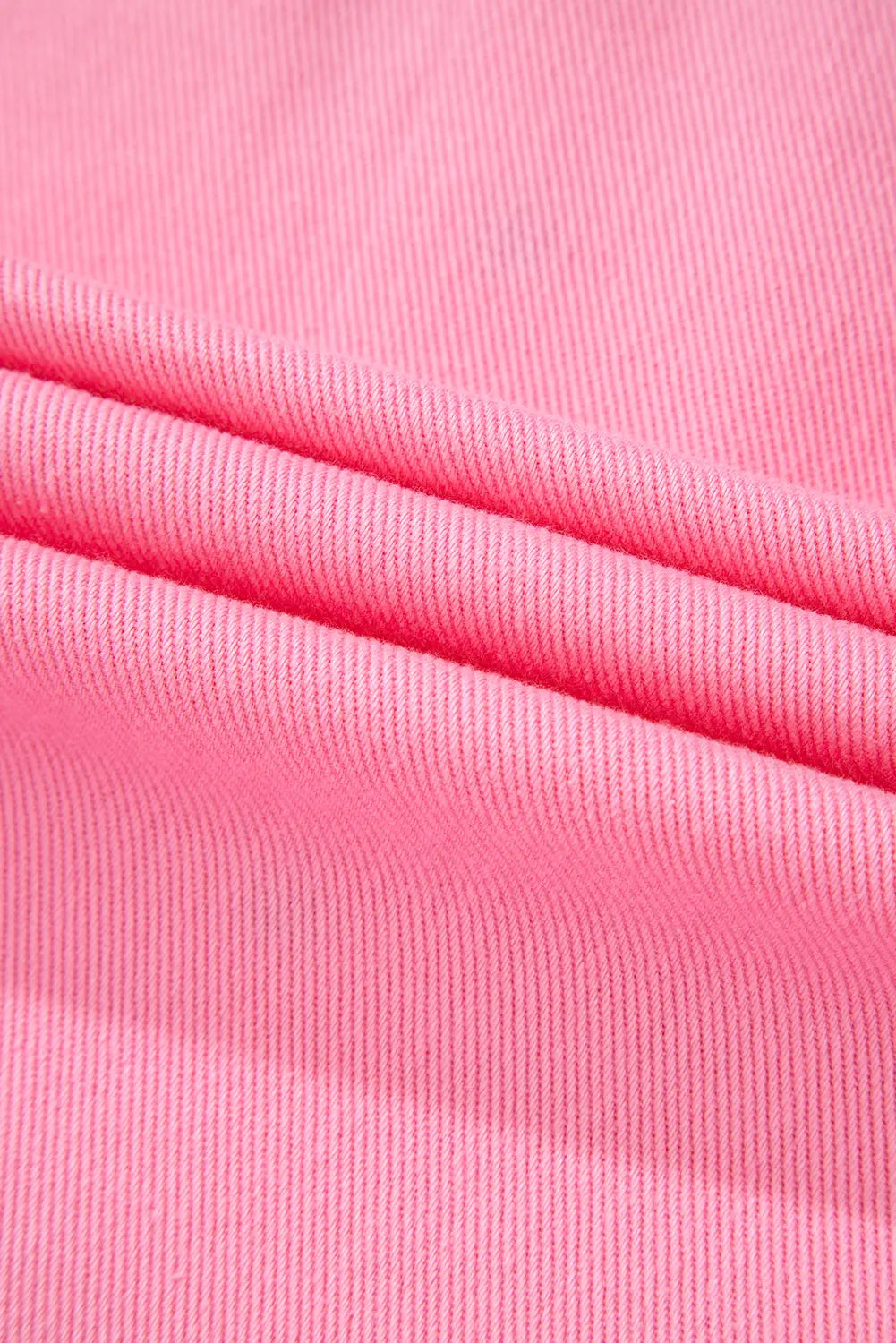 A close-up of bright pink ribbed knit fabric with soft folds showing the texture and weave.