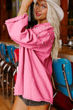 Woman wearing a pink jacket with pearl embellishments in a casual setting.