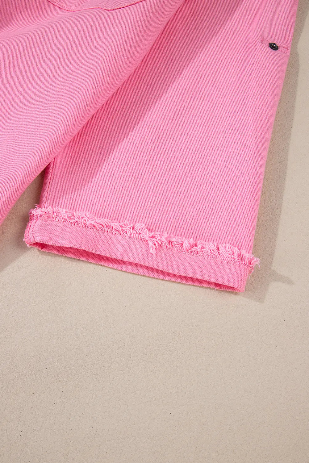 Close-up of a pink garment with frayed edge on a beige background