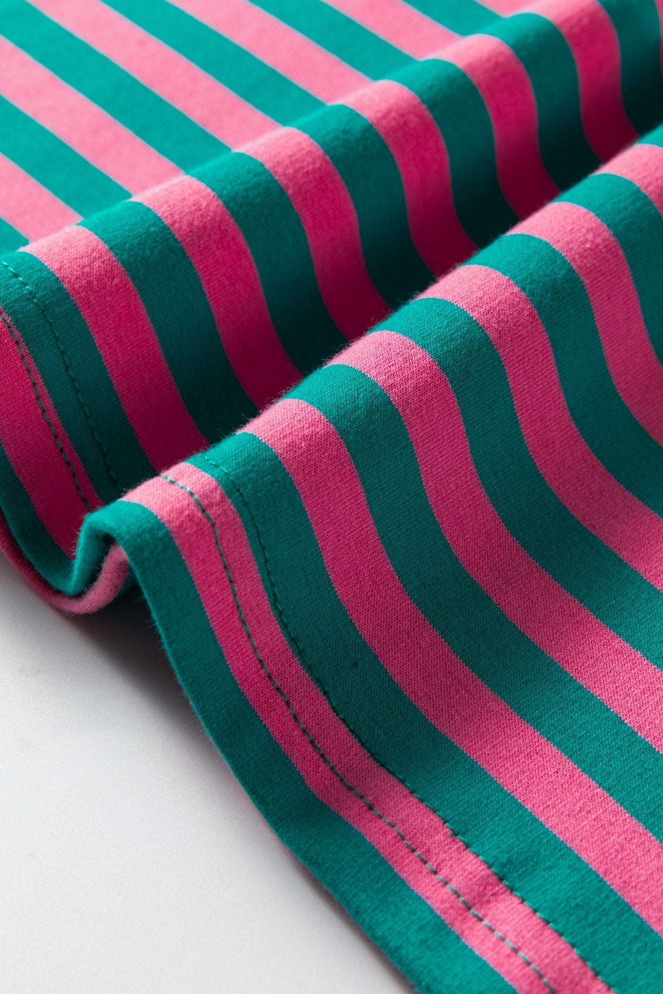 Close-up of pink and green striped fabric on a light gray background
