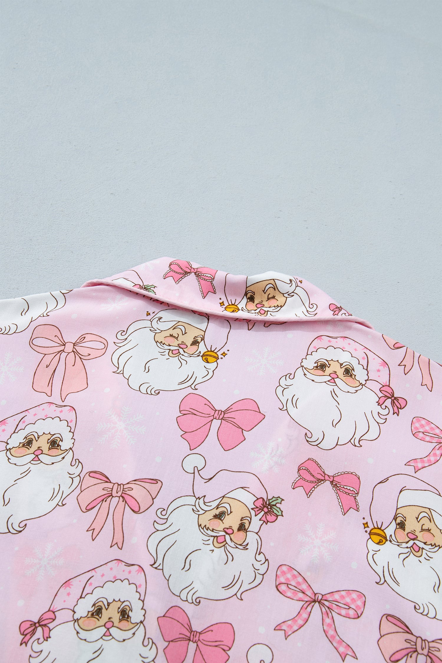 Pink pajama top with Santa face, white beard, and pink bow print.