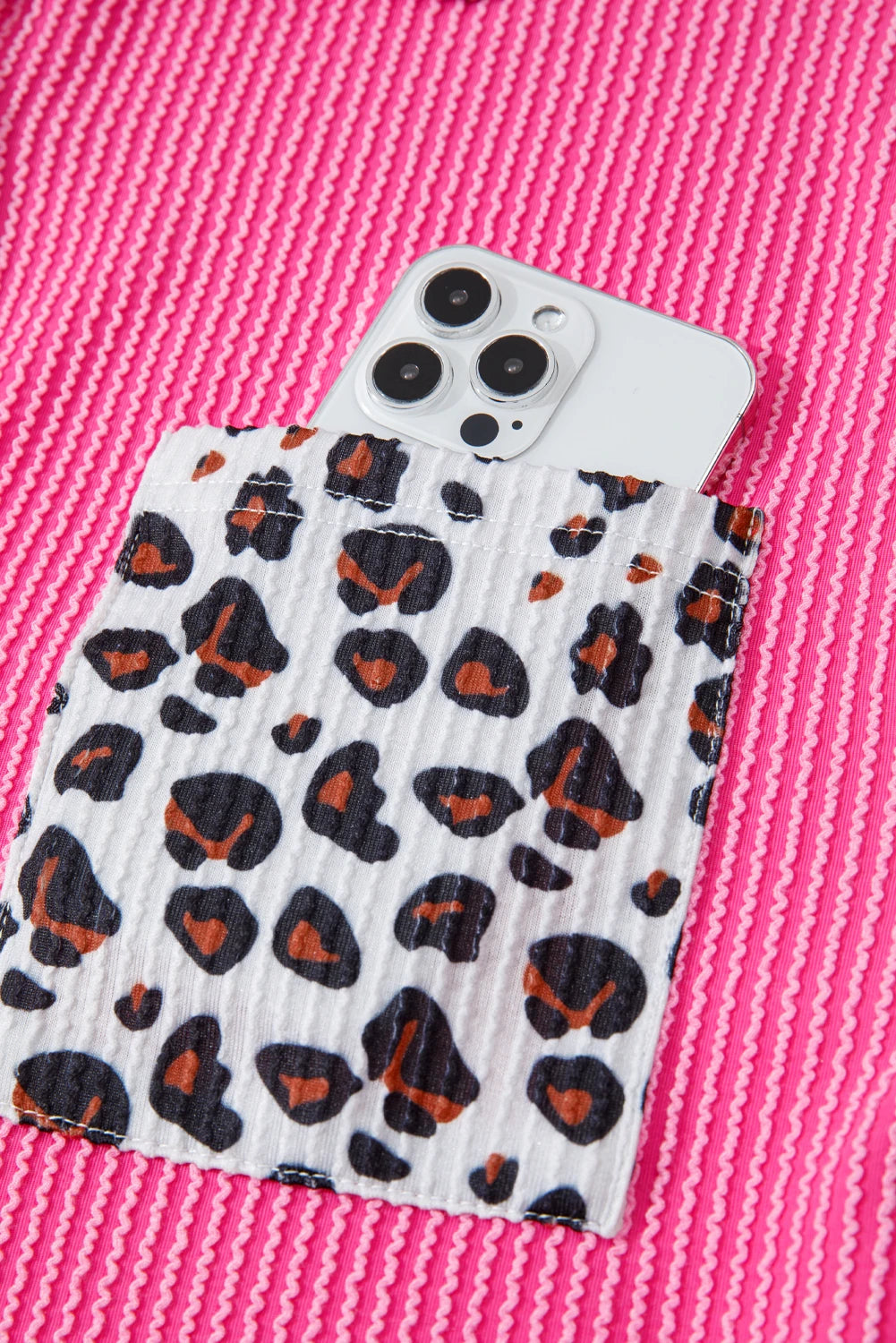 Phone case with leopard print design on a pink textured background.