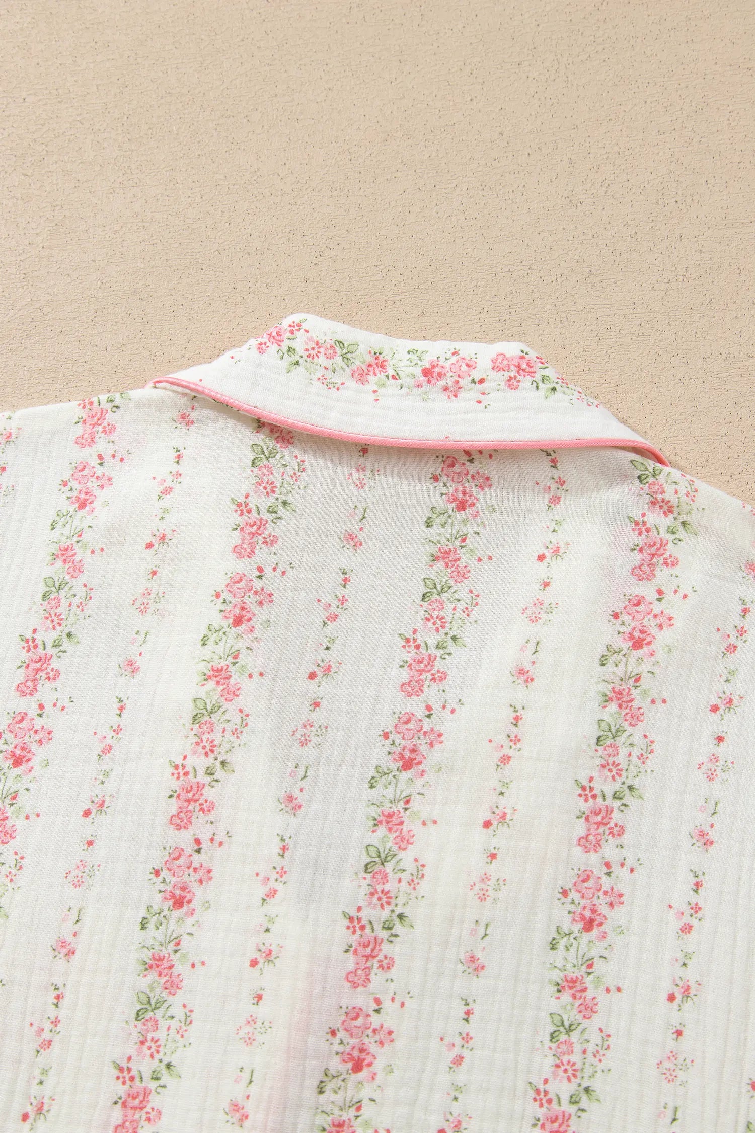 Close-up of white gauze shirt with pink-green floral stripes and pink-trimmed collar.