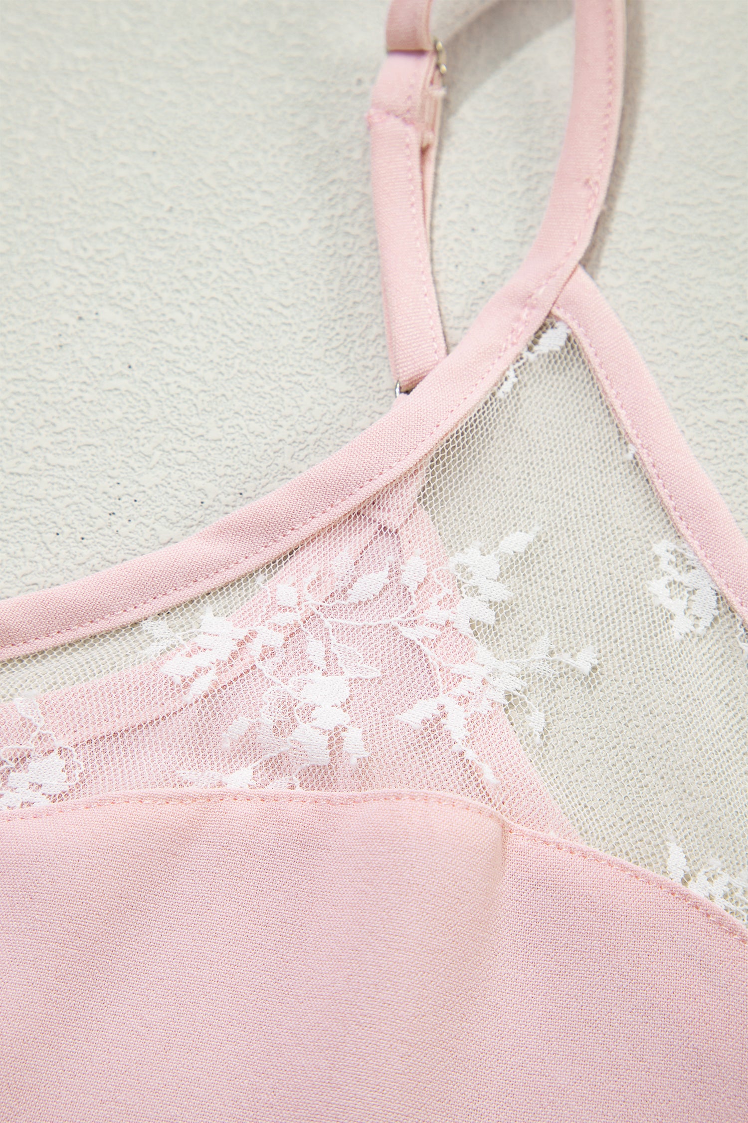 Close-up of a pink bra with floral lace details on a light background