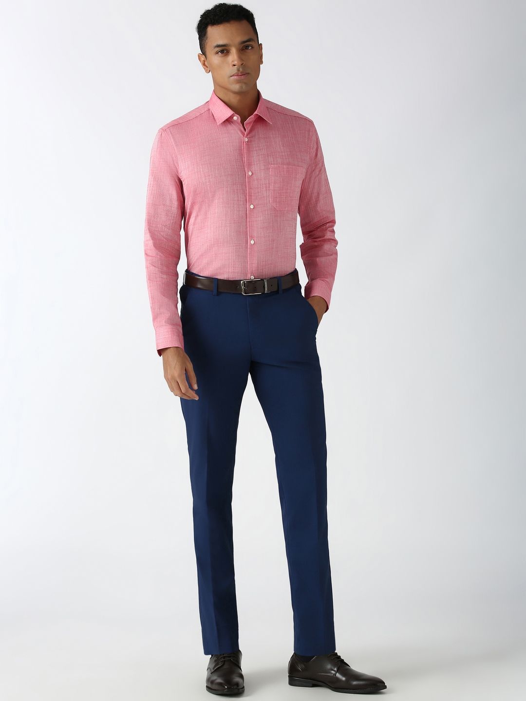 Man wearing a pink checkered shirt and blue pants on a white background
