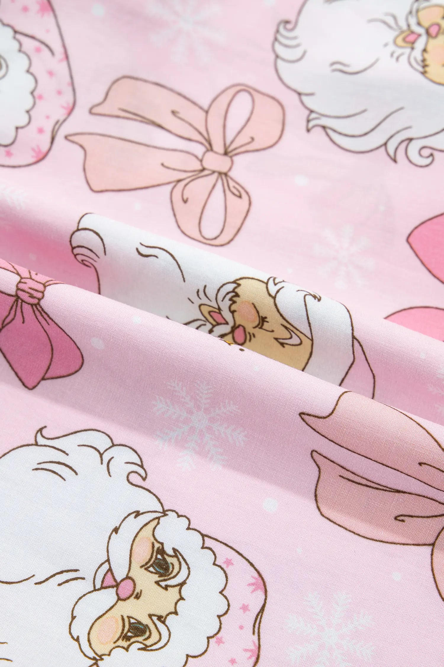 Close-up of pink fabric with Santa faces, bows, and snowflake print.