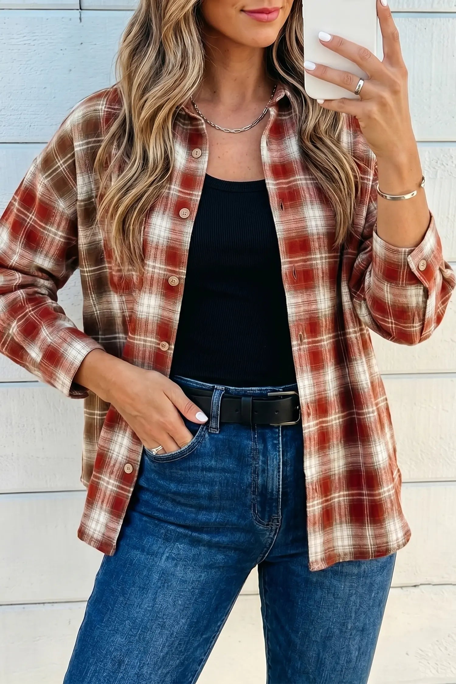 Woman wearing a plaid shirt, black top, and blue jeans against a light wooden panel background.