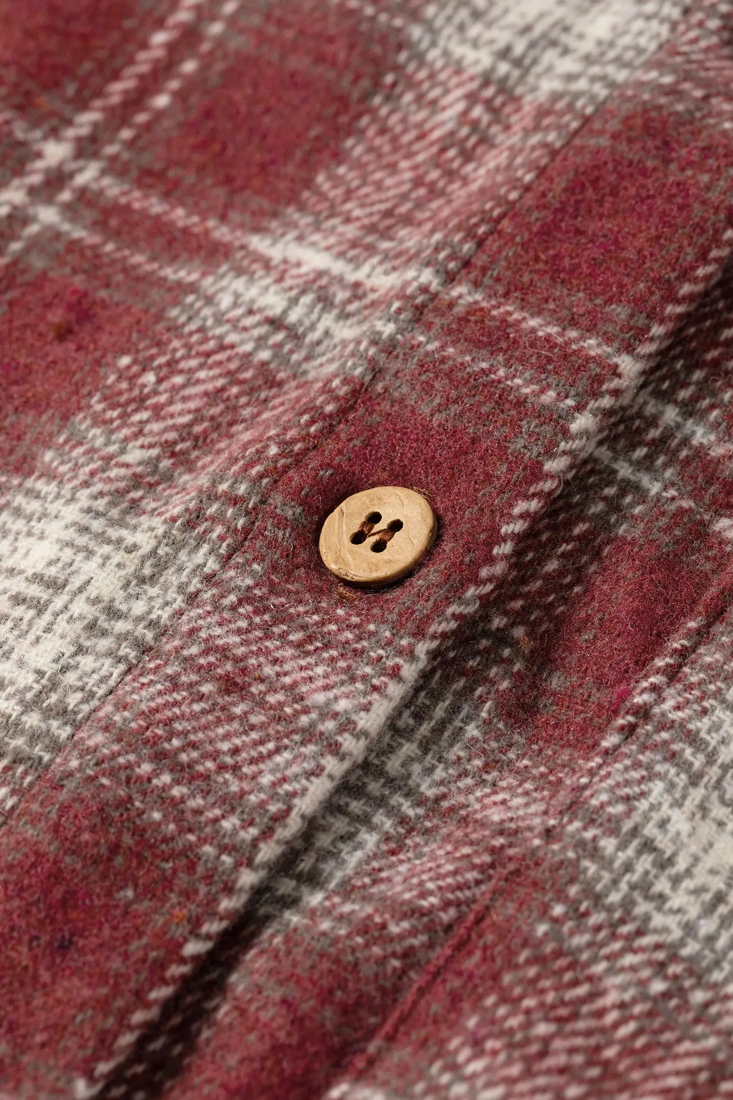 Close-up of a plaid fabric with a button, featuring red and gray colors.