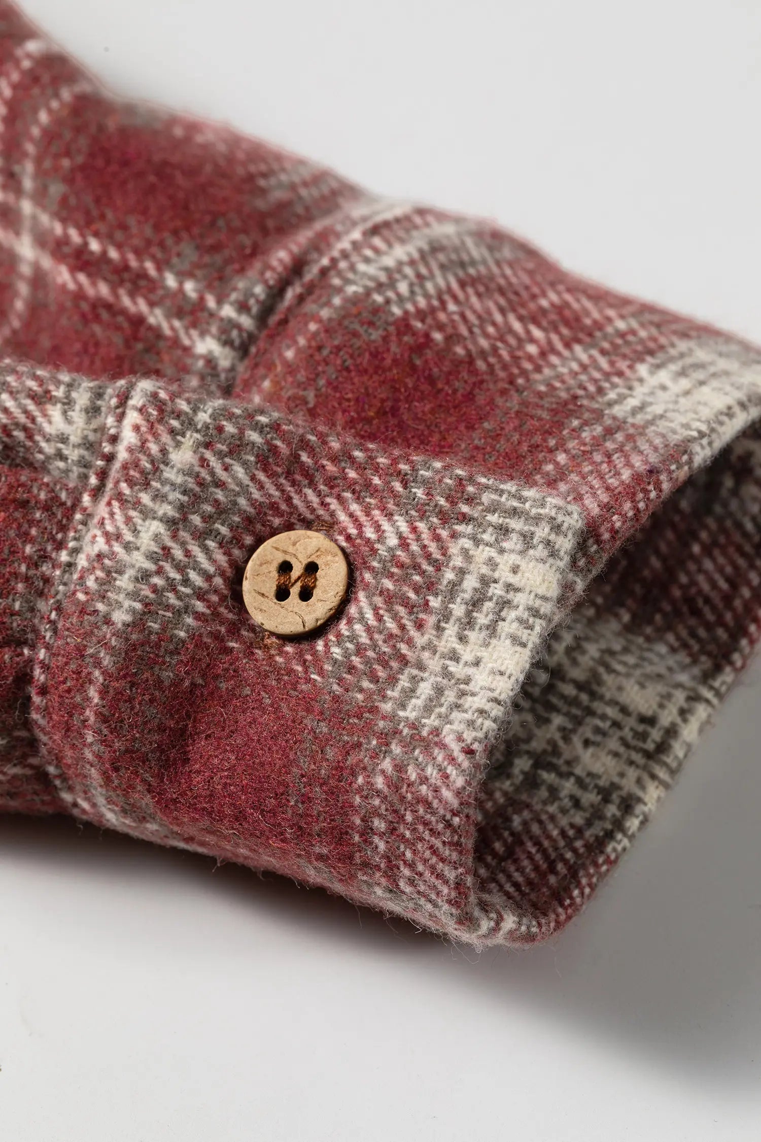 Close-up of a plaid fabric with a button on a light gray background