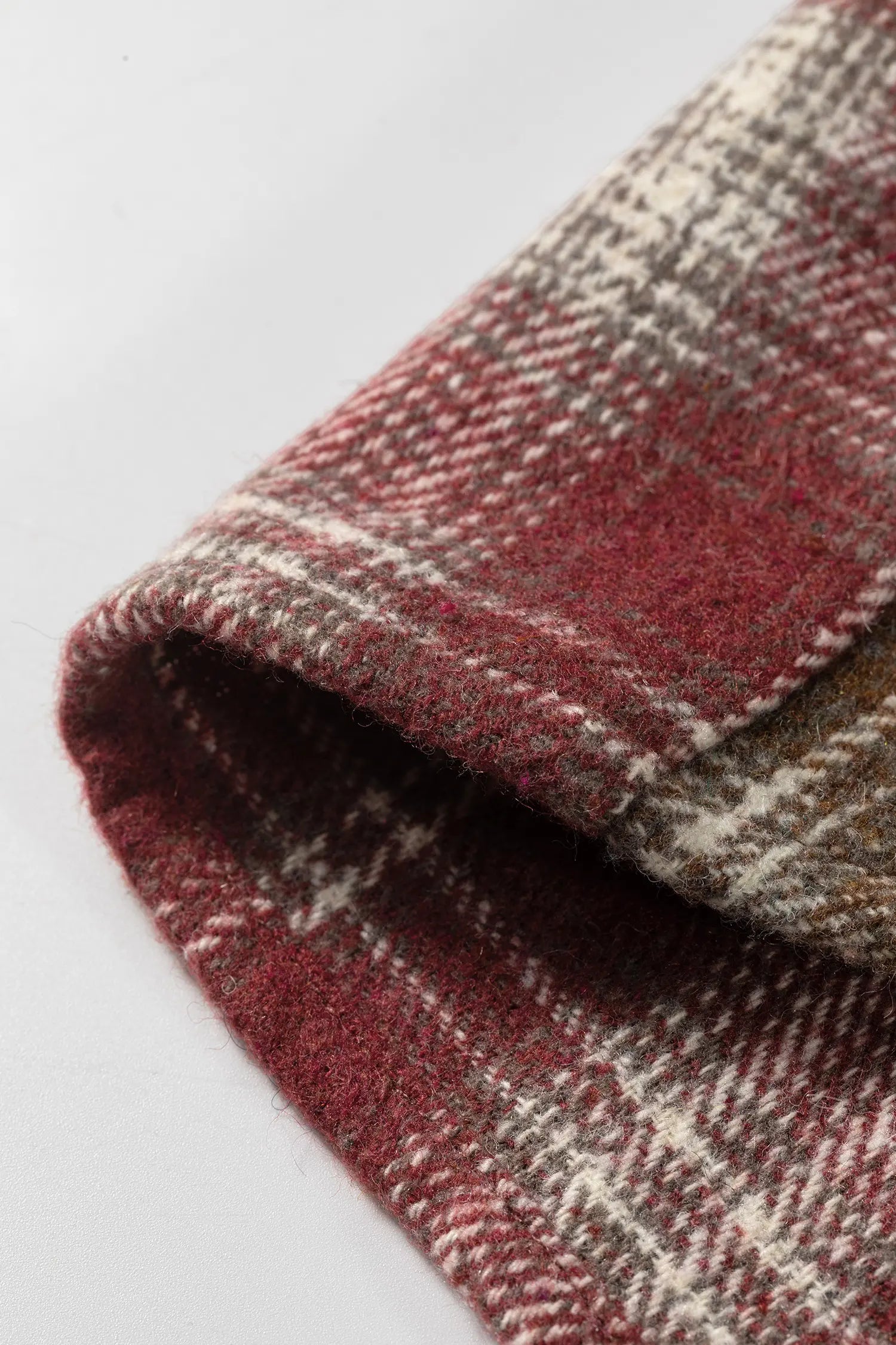 Close-up of a plaid fabric with red and beige pattern on a white background