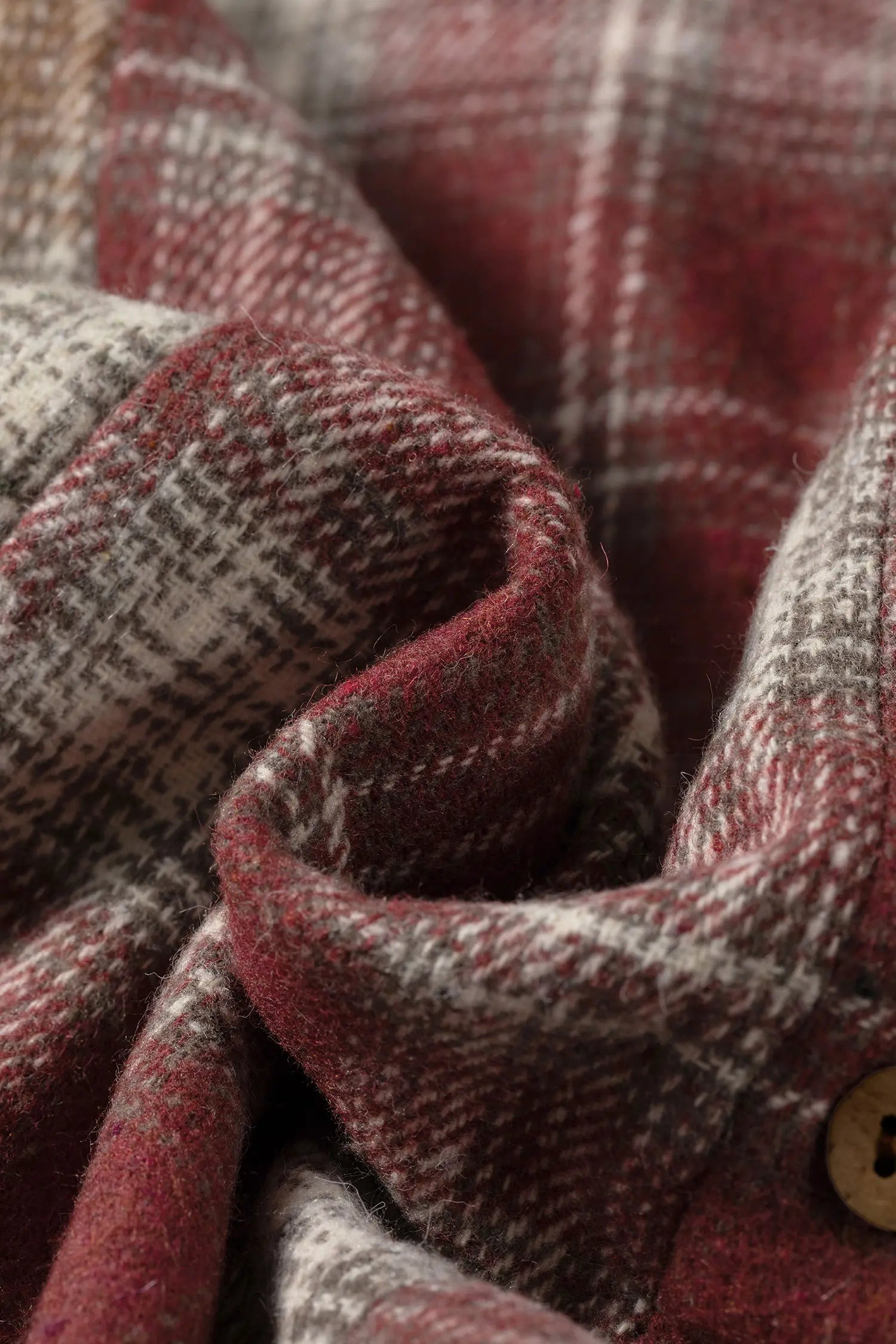 Close-up of plaid fabric with a button, showing texture and pattern details.