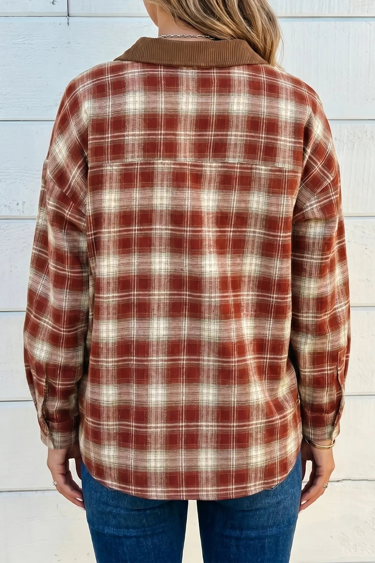 Person wearing a red and beige plaid shirt against a light blue wooden panel background