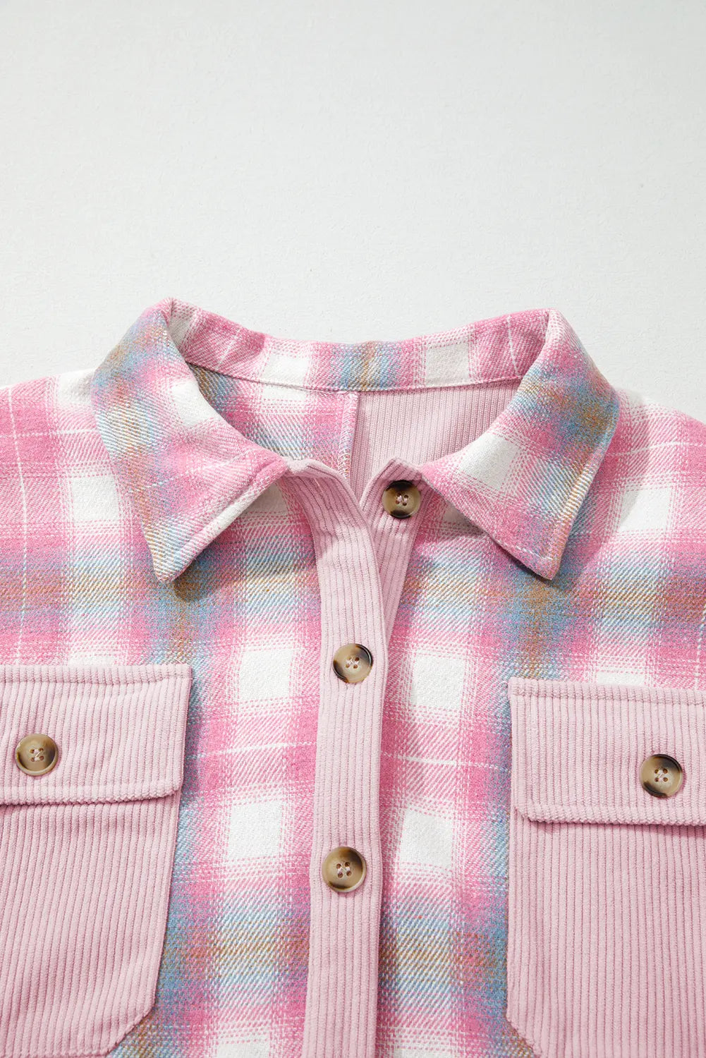 Close-up of a pink plaid shirt with gold buttons on a white background