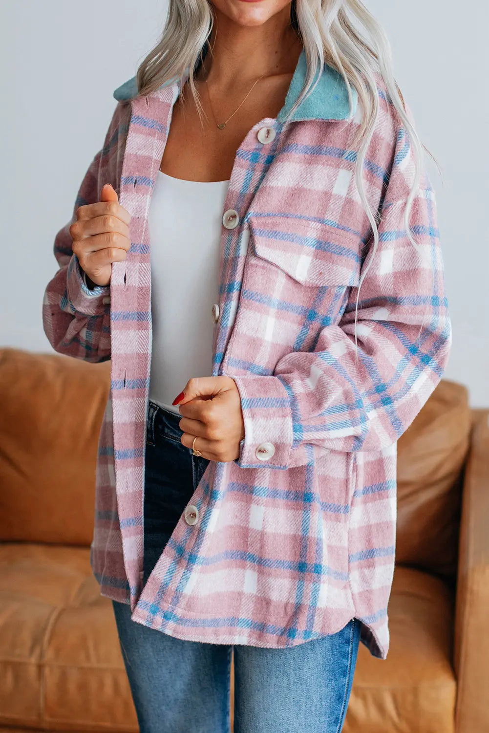 Person wearing a plaid shirt over a white top with a blurred background