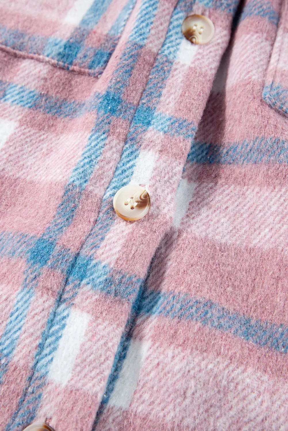 Close-up of a pink and blue plaid fabric with buttons.