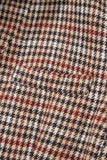 Close-up of a houndstooth pattern fabric with black, red, and beige colors.