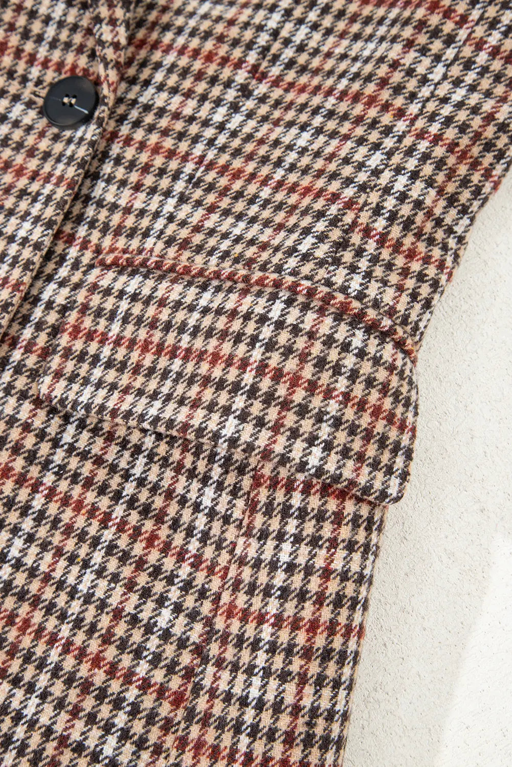 Close-up of a plaid patterned fabric with a button and white lining.