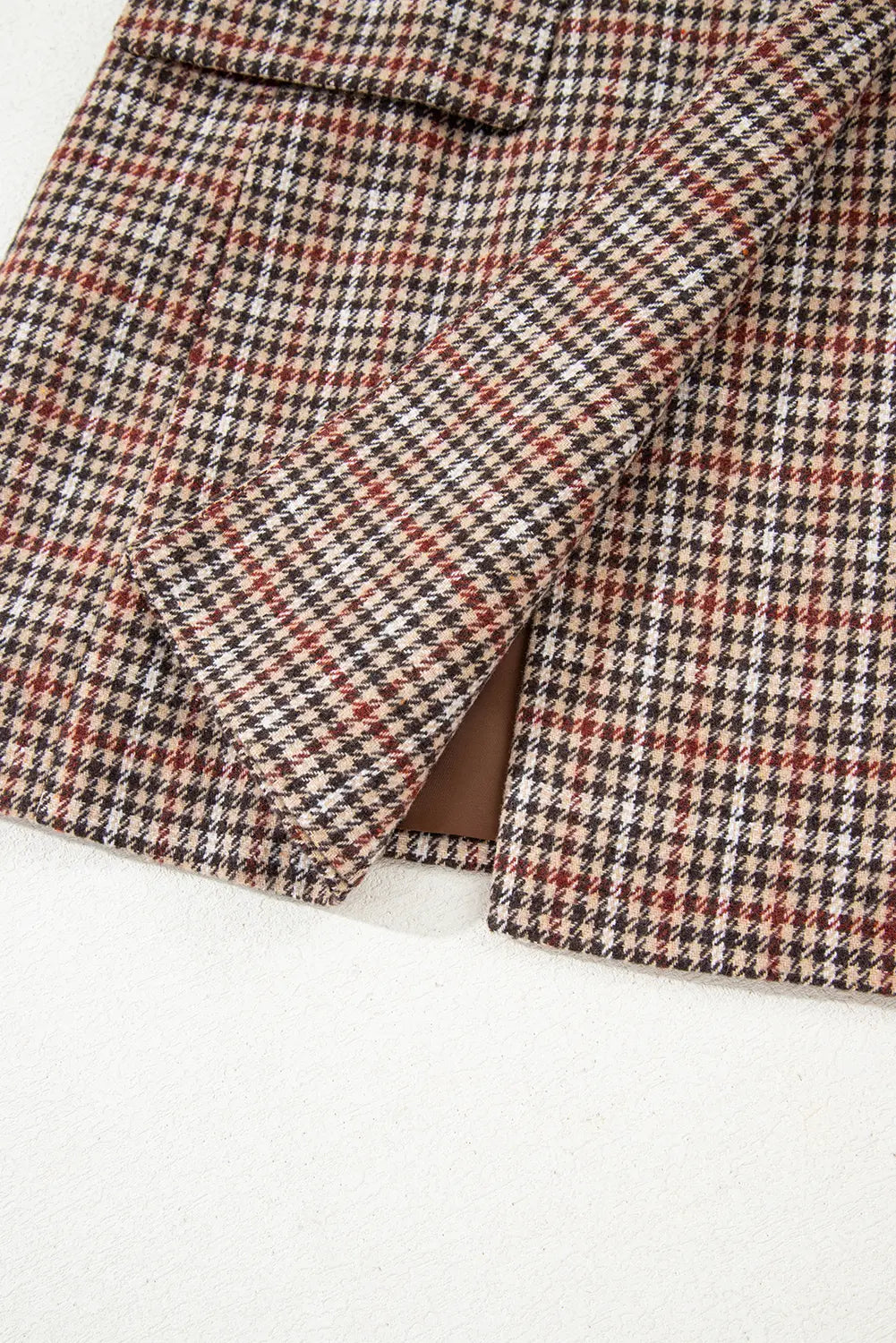 Close-up of a plaid fabric with brown, black, and white pattern on a white background
