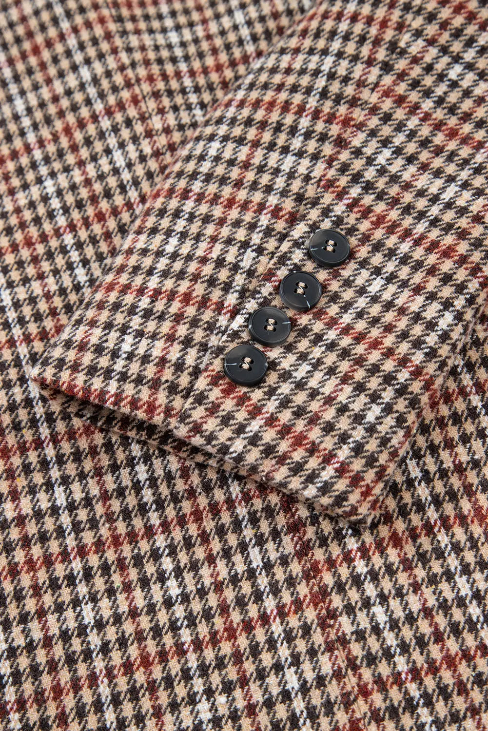 Close-up of a patterned fabric with buttons on a checkered shirt.