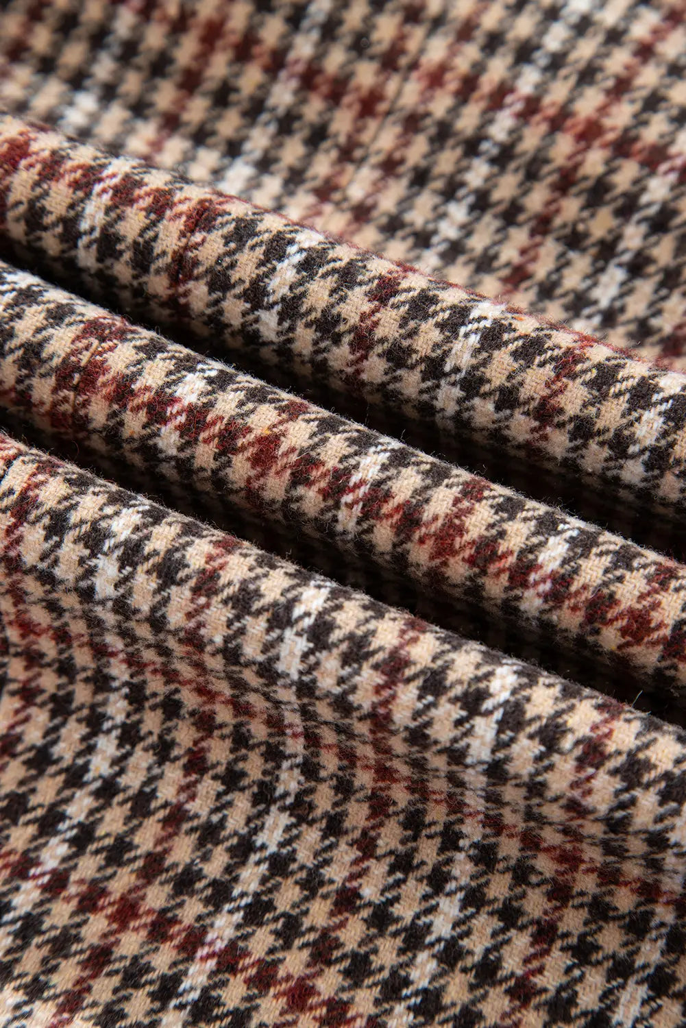 Close-up of houndstooth pattern fabric with red, black, and beige colors.