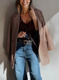 Woman wearing a plaid coat, black top, and blue jeans against a neutral wall.