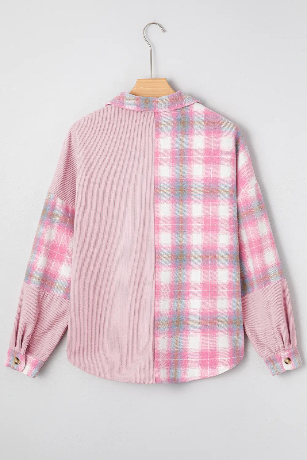 Pink plaid shirt on a hanger against a light gray background