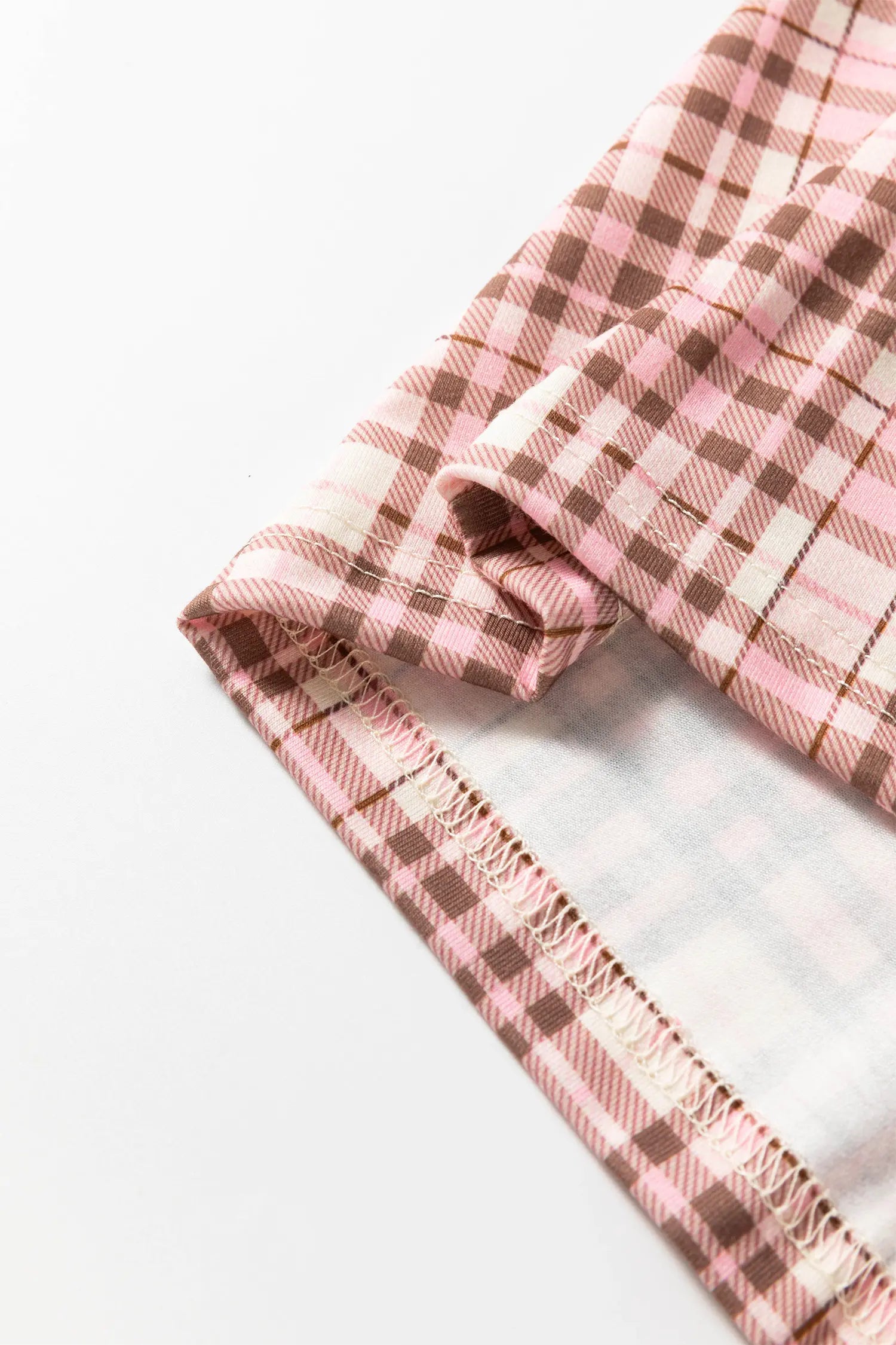 A close-up of a folded plaid fabric with a pink and brown checkered pattern.