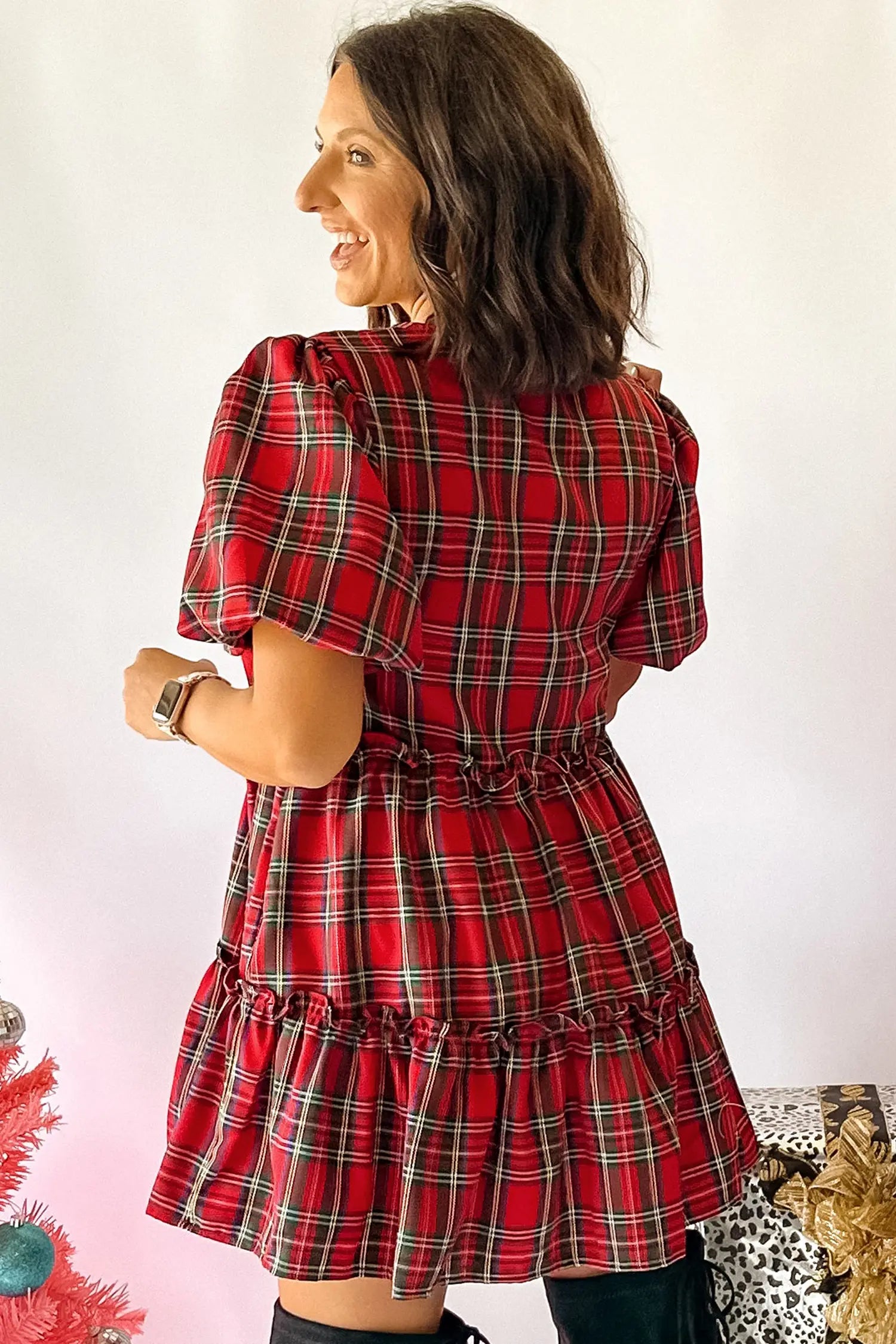 A woman wearing a red and black plaid puff-sleeve mini dress, shown from the back against a plain white background.