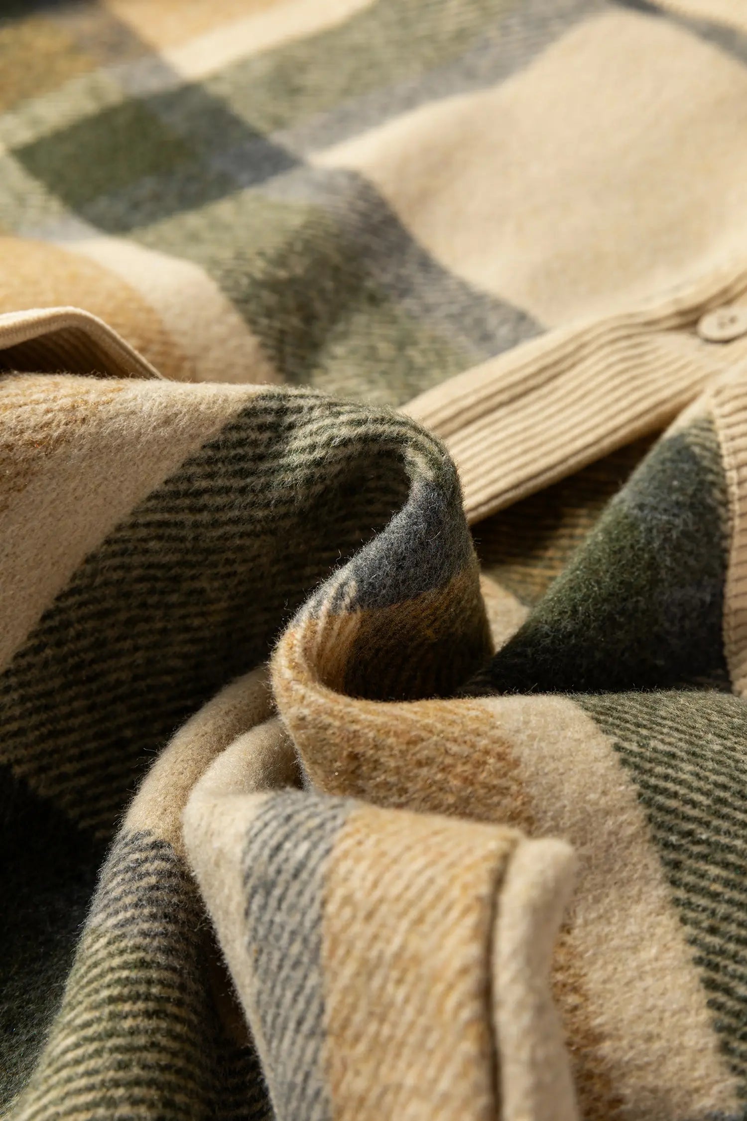 Close-up of a plaid fabric with brown, green, and beige colors.