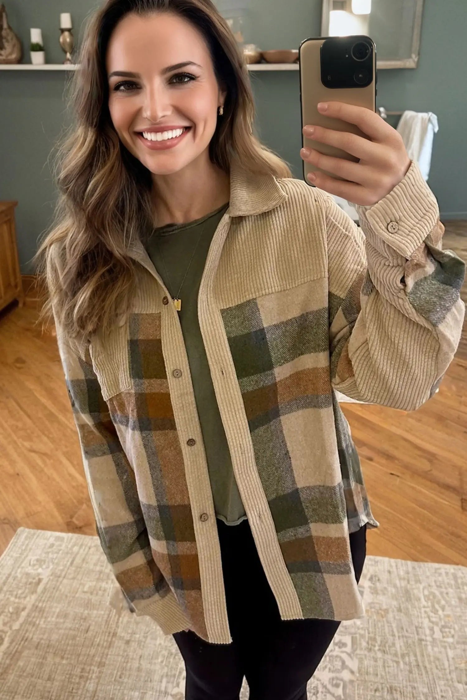 Woman taking a mirror selfie wearing a plaid shirt in a home setting.