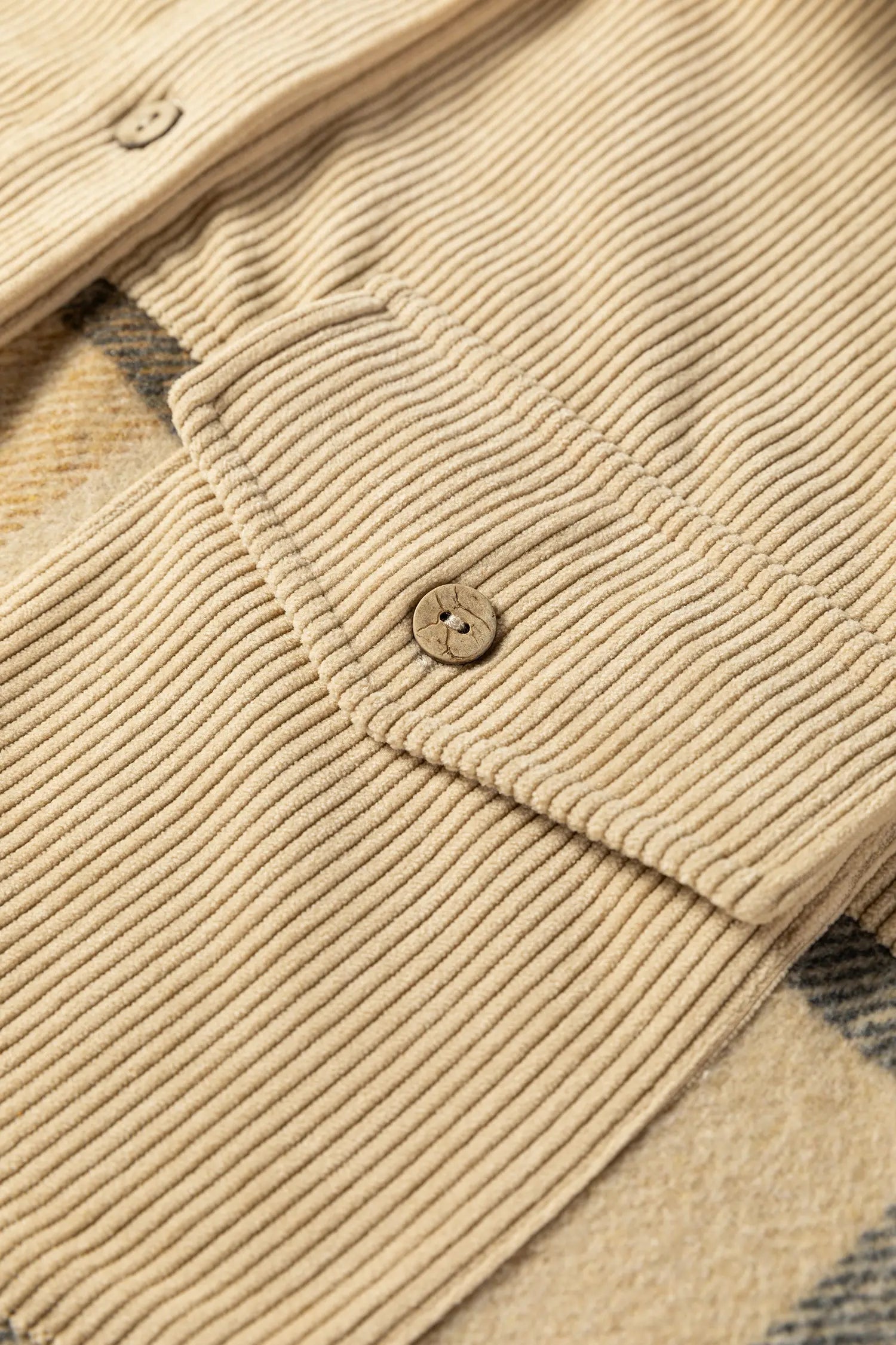 Close-up of a beige corduroy jacket with plaid pattern