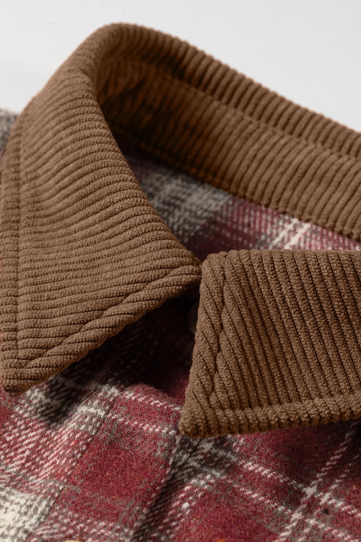 Close-up of a brown ribbed collar on a plaid fabric background