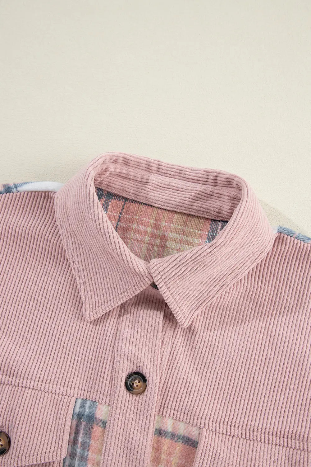 Close-up of a pink striped shirt with plaid accents on a beige background