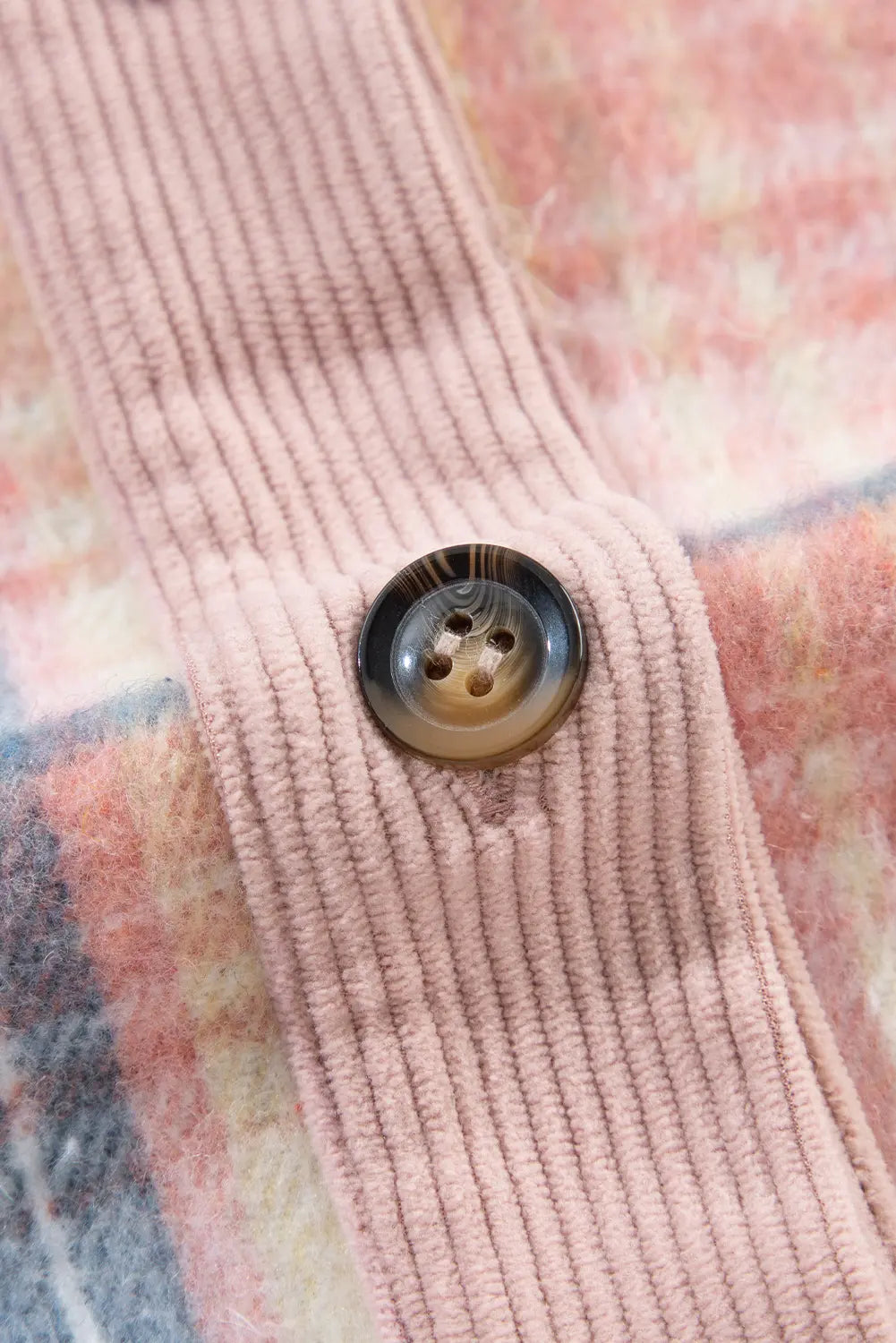 Close-up of a pink textured fabric with a button on a floral background