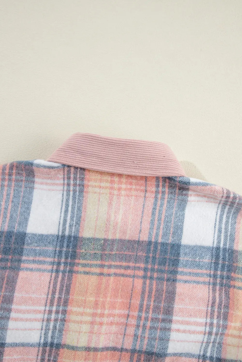 Close-up of a plaid shirt with a pink collar on a beige background