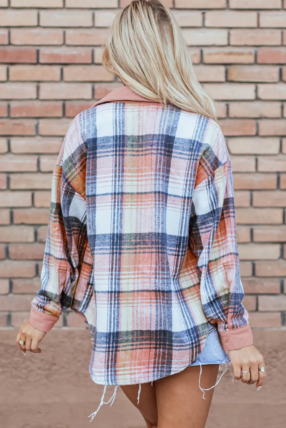Person wearing a plaid shirt with a brick wall background