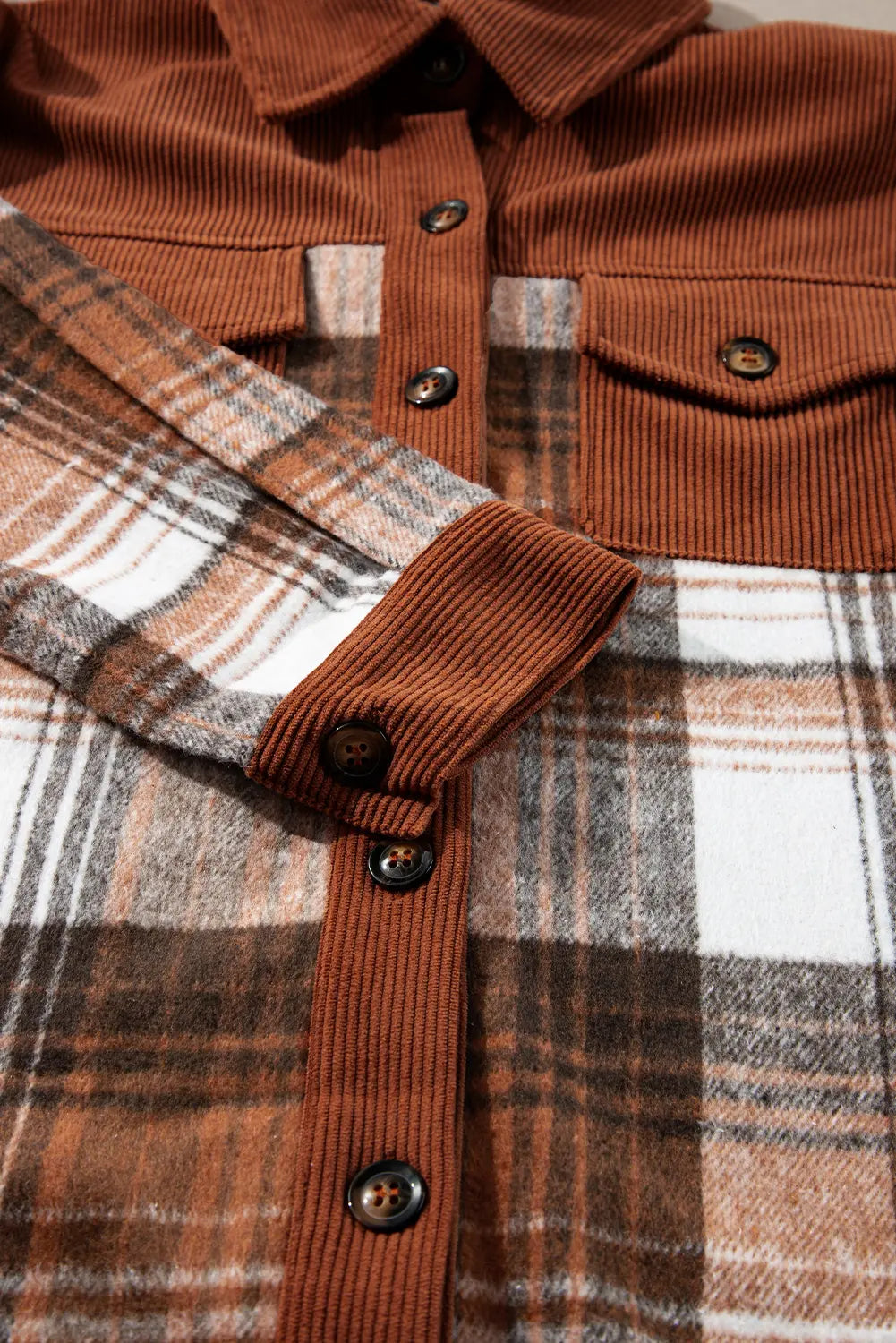 Close-up of a brown corduroy shirt with plaid collar and cuffs.