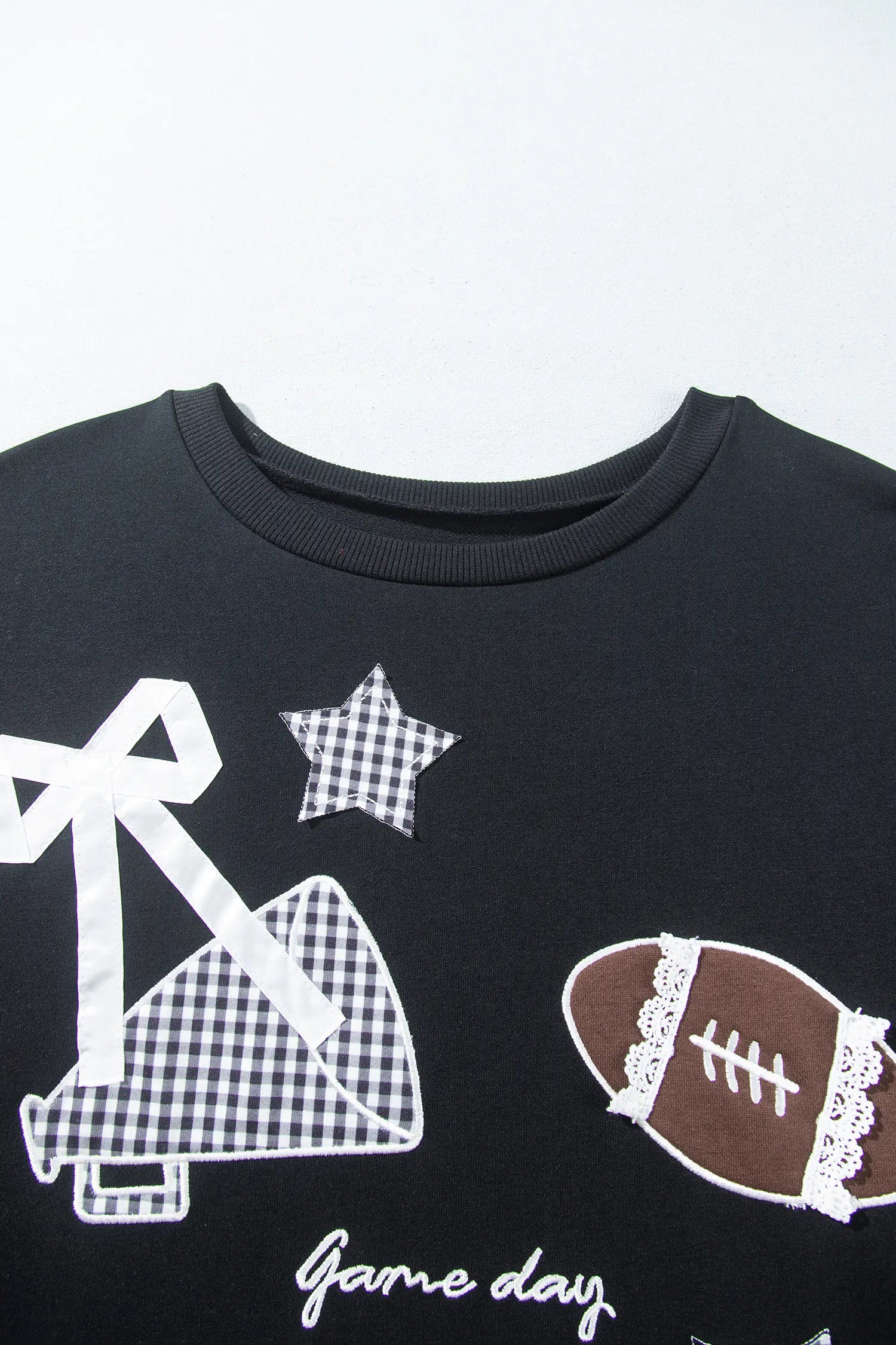 Black crewneck sweatshirt with megaphone, football, star patches, and “Game Day” text.