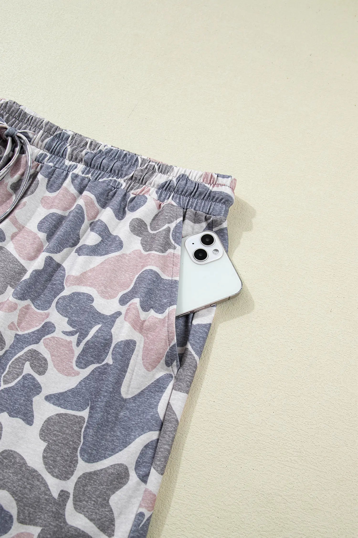 Camouflage-patterned shorts with a smartphone on a beige background